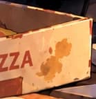 Worn pizza-box corner at the edge of the desk