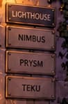 FOUR CLIENT PLAQUES. Lighthouse, Nimbus, Prysm and Teku appear beside the doorway. These names identify launch-era client software, rather than four validators or four physical institutions.