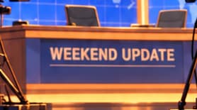THE WEEKEND UPDATE DESK. The desk names the segment where Musk played Lloyd Ostertag and discussed Dogecoin. The recognisable setting is an artistic interpretation, not a frame copied from the broadcast.