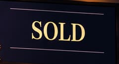 THE SOLD SCREEN. The large illuminated SOLD screen announces that the auction is over. It points to the moment ConstitutionDAO lost the contest, rather than a purchase by the community. The screen's placement and appearance are artistic inventions.