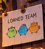 THE LOANED ROSTER. The wall sheet reads LOANED TEAM above three creature portraits. It makes the scholarship arrangement visible: the player has access to someone else's Axies. This invented roster represents borrowed assets, rather than proof of ownership.