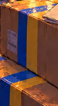 BLUE AND YELLOW TAPE. Packing tape carries Ukraine’s colours across neighboring cartons: a symbolic connection between solidarity and practical support.